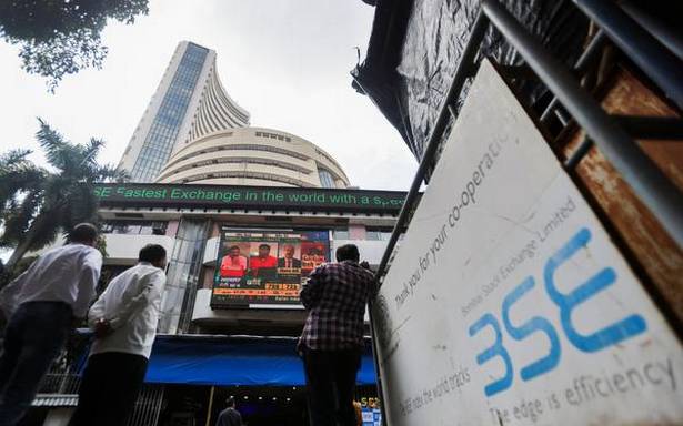 People stand outside the Bombay Stock Exchange BSE after Sensex surpassed the